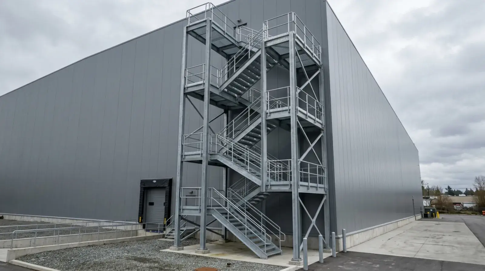Galvanized structural steel stair tower with landings and guardrails installed inside an Amazon distribution warehouse in Delta, BC