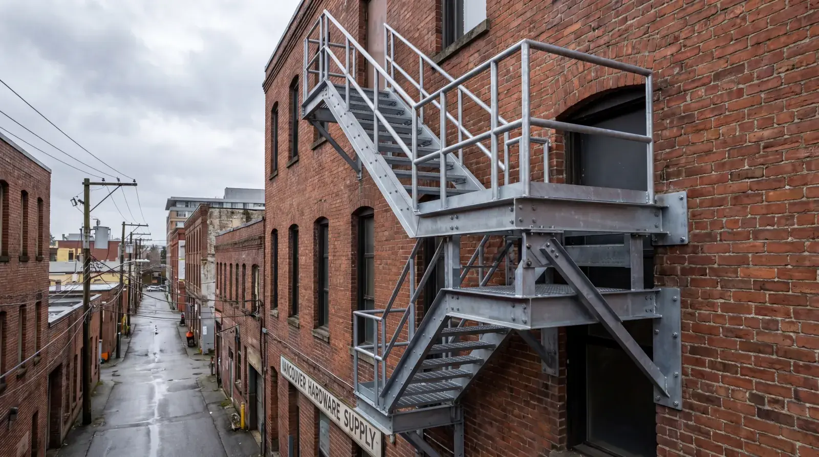 Exterior steel fire escape on a Vancouver heritage building being inspected by a fabricator