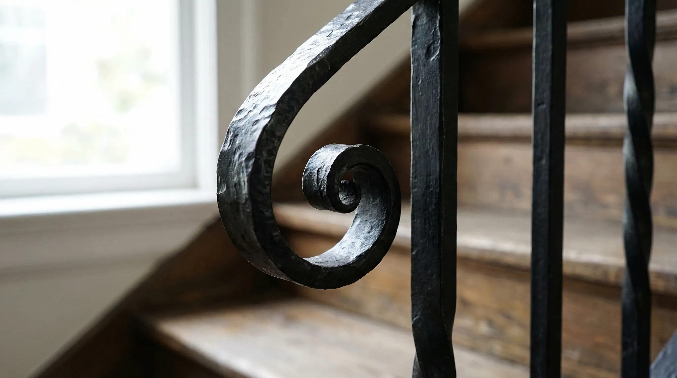 Hand-forged scroll detail on a custom black iron railing in a Vancouver heritage staircase