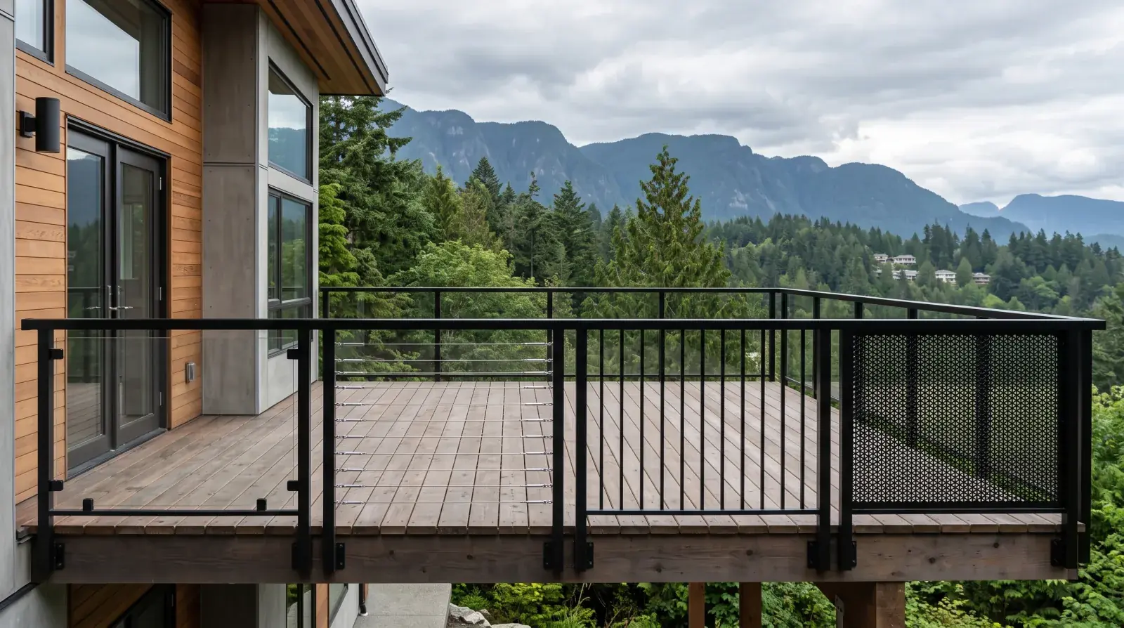 Modern black steel deck railing showing glass, cable, steel picket, and perforated mesh infill sections on a North Vancouver home overlooking mountains