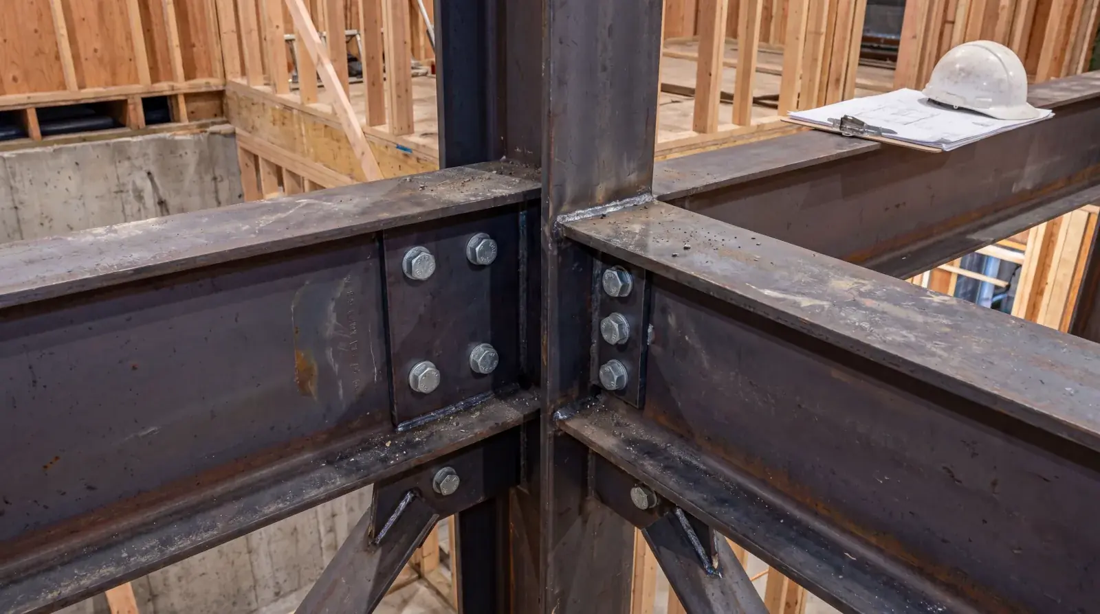 Structural steel moment connection with stiffener plates and bolted flanges for seismic resistance