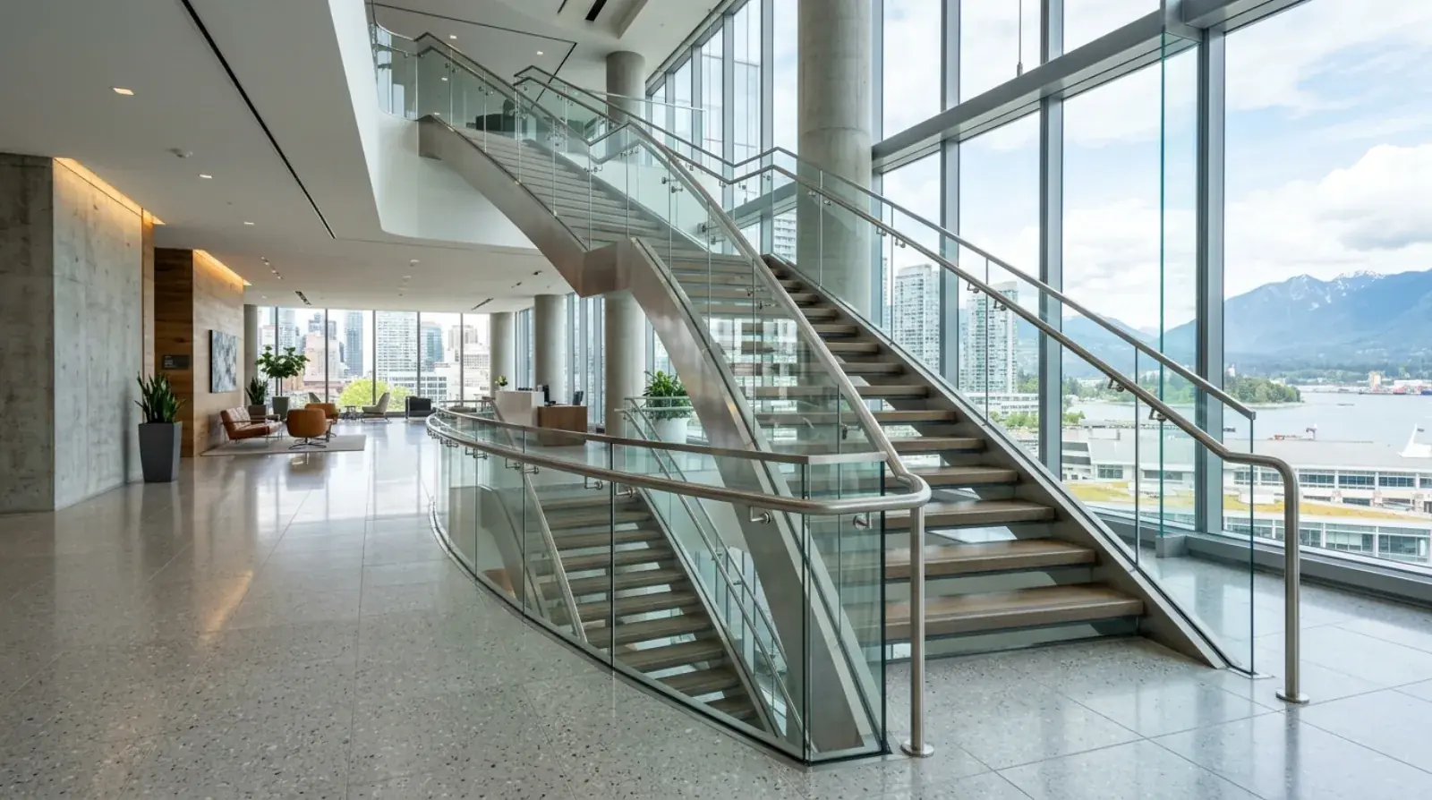 Frameless glass and stainless steel balustrade wrapping a feature stair in a modern downtown Vancouver office lobby