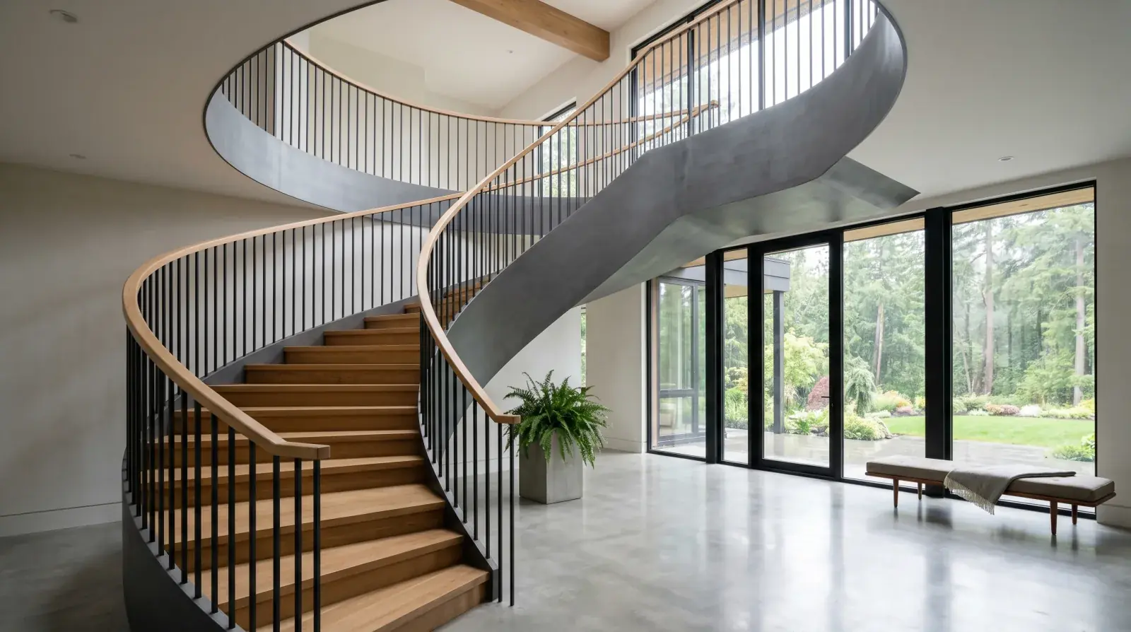 Helical curved steel staircase with continuous stringer rising through a double-height Vancouver custom home foyer