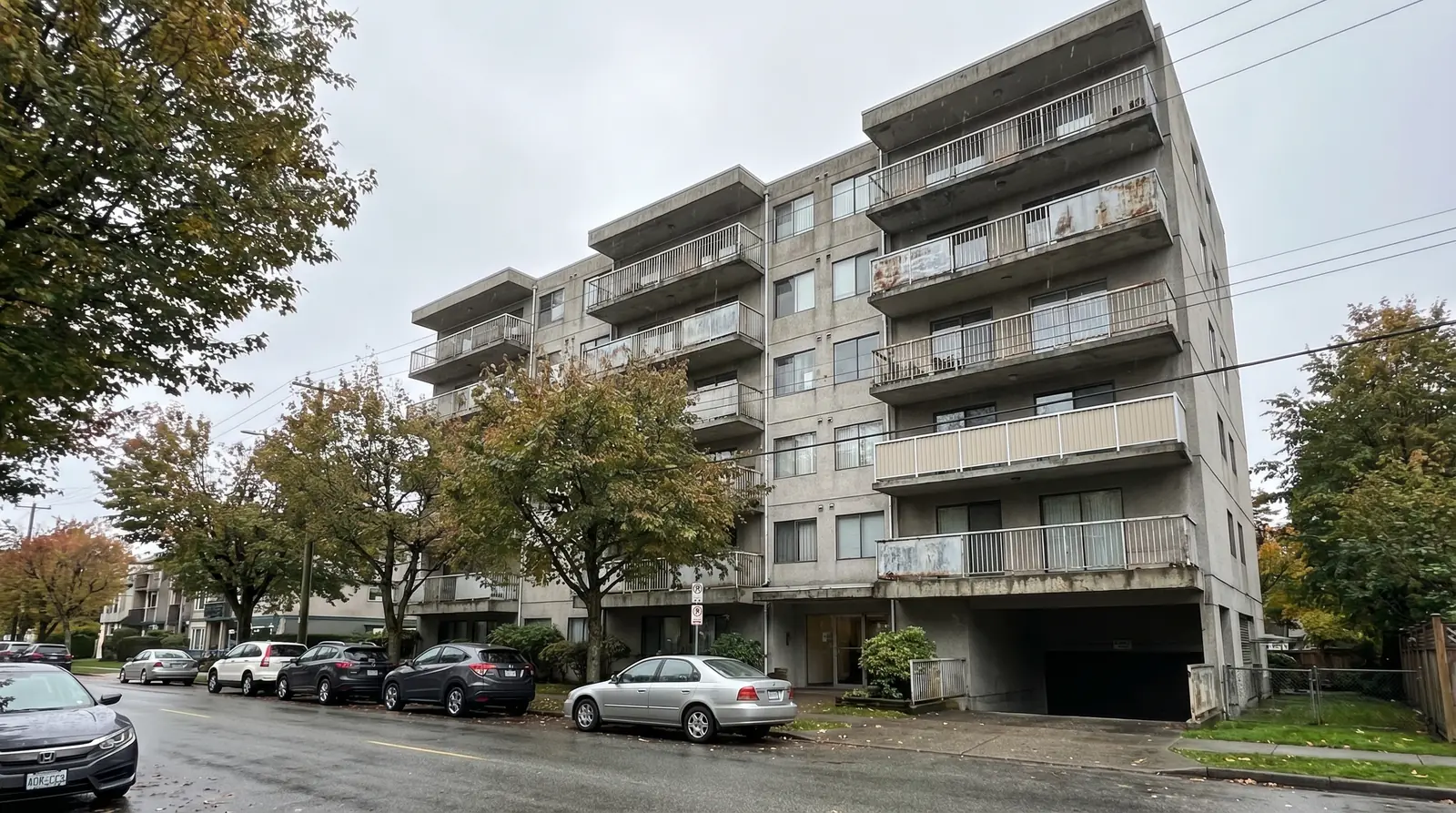 Mid-rise concrete condo building in Metro Vancouver with aging aluminum balcony railings showing signs of corrosion