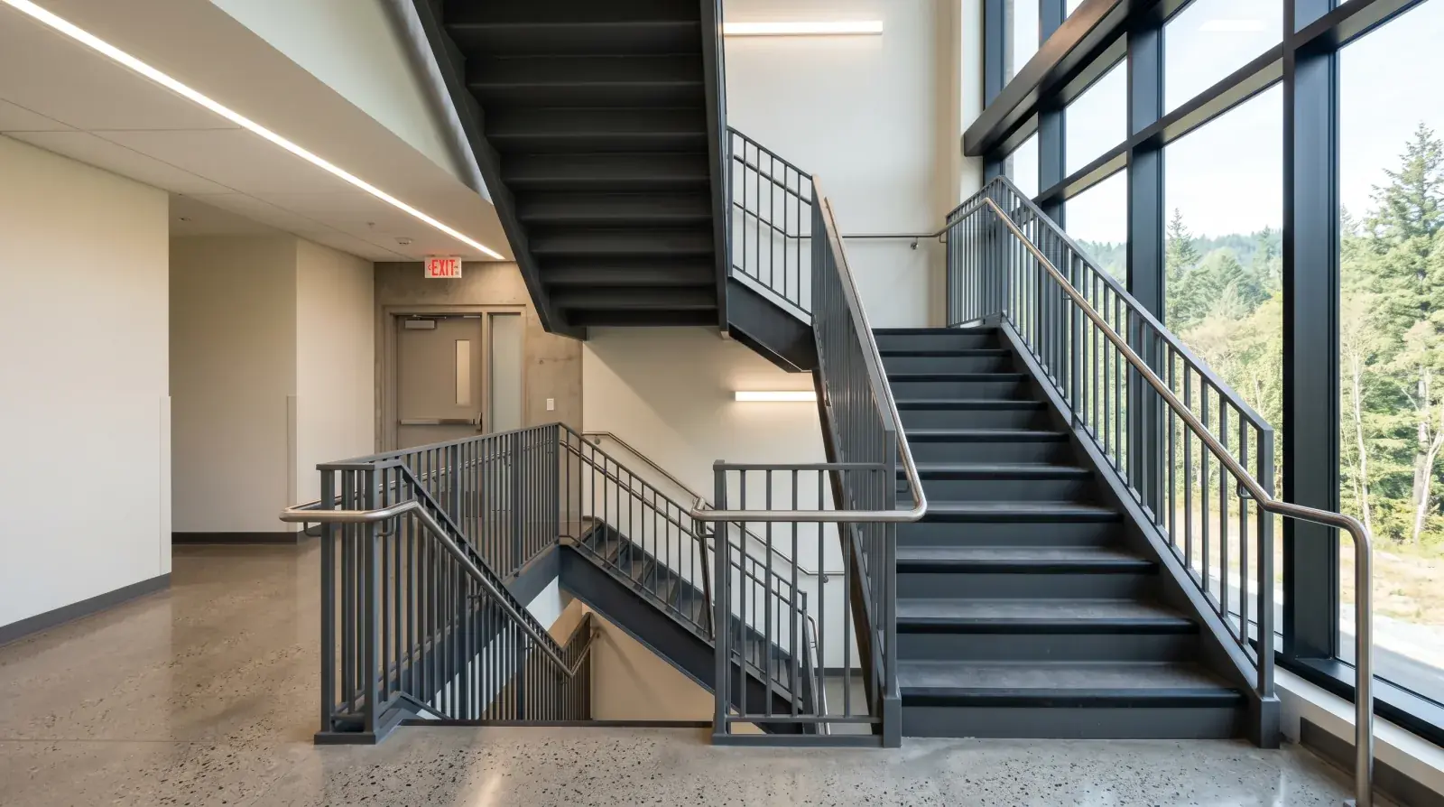 Modern powder-coated steel egress staircase with steel picket guardrails in a British Columbia hospital interior