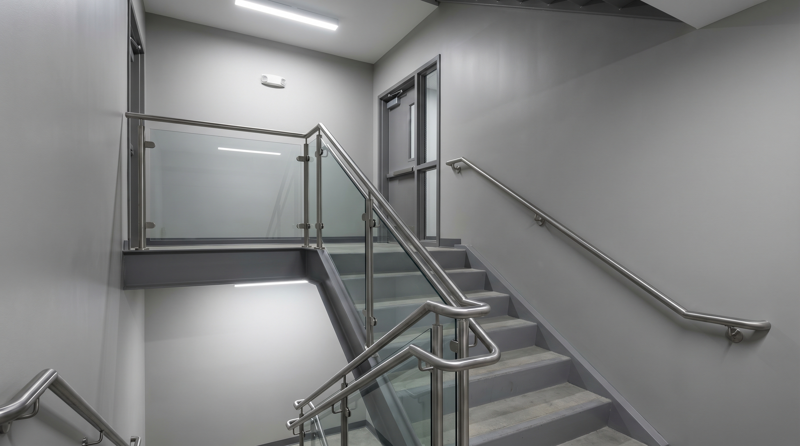 Commercial stairwell with modern glass and stainless steel railing system in a multi-storey building