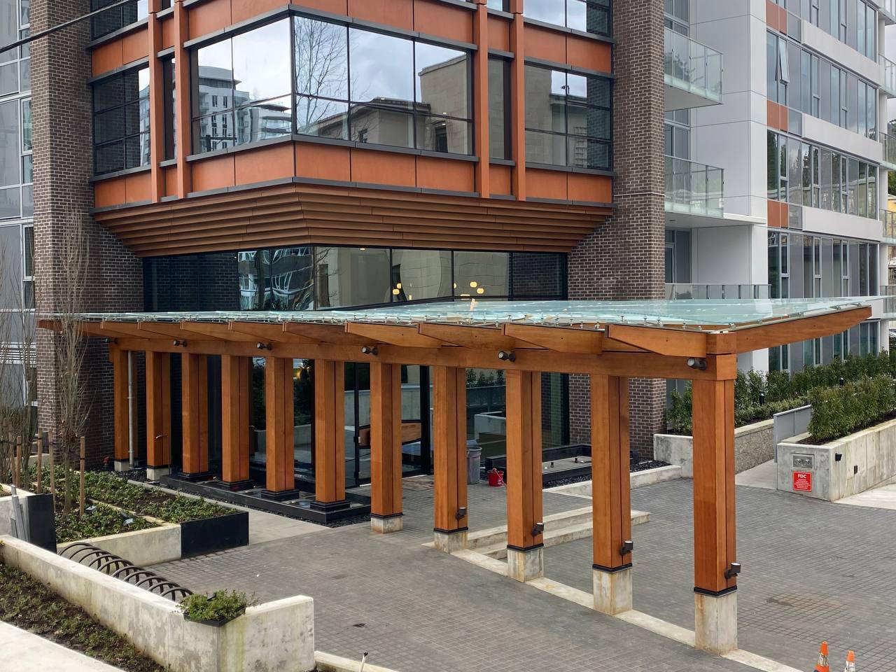 Wood, steel, and glass entry canopy fabricated and installed by Jeff and Simon Ironworks at a Burnaby high-rise entrance