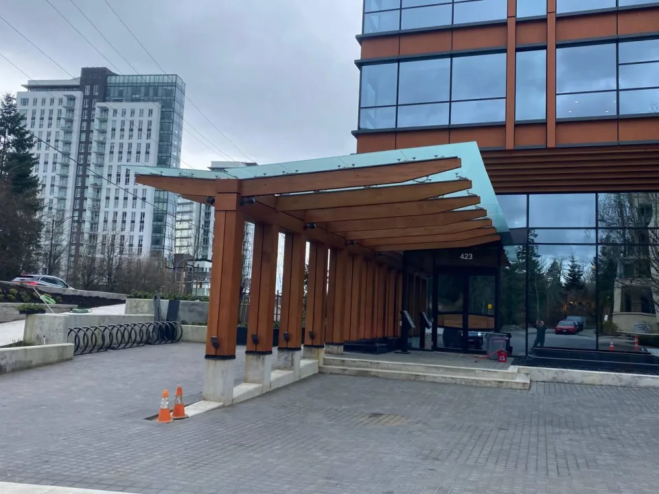 Custom structural steel and glulam timber entry canopy with glass roof fabricated for a modern high-rise in Burnaby, BC