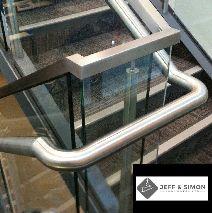 Brushed stainless steel handrail with glass panel railing on a commercial staircase