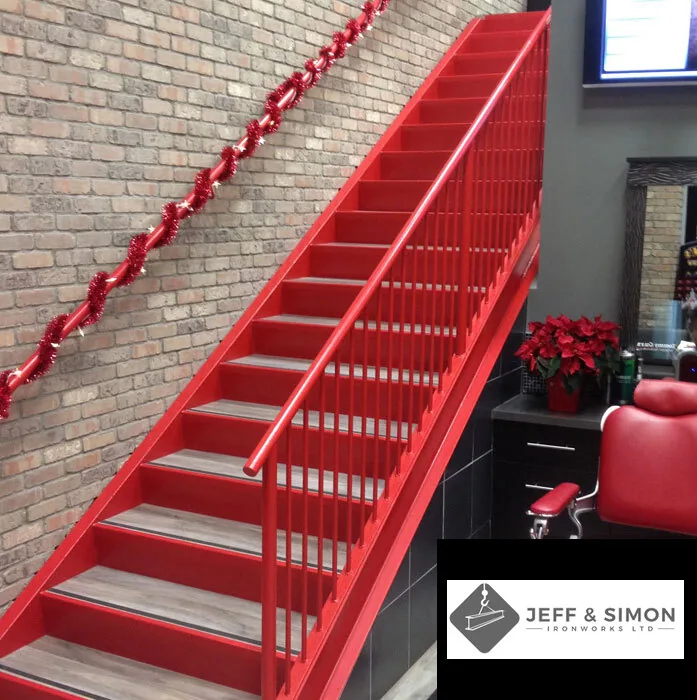 Custom red powder-coated steel staircase with metal railing inside a commercial interior space